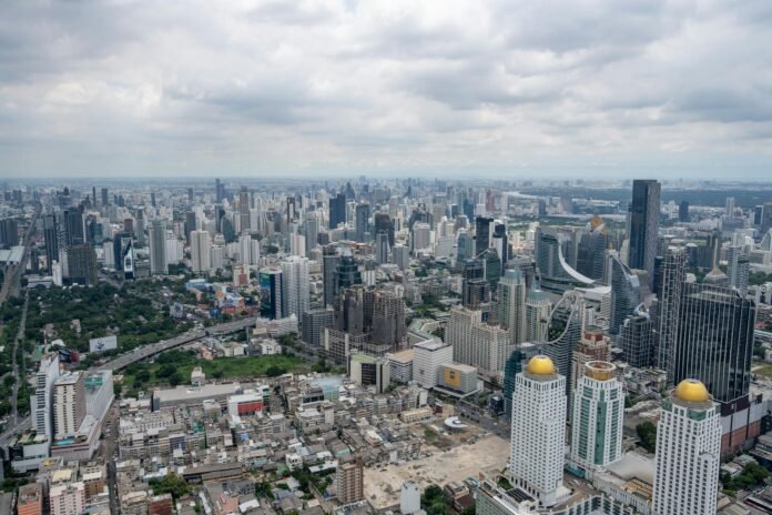 Stunning aerial view of Bangkok's modern skyline under clouded skies.