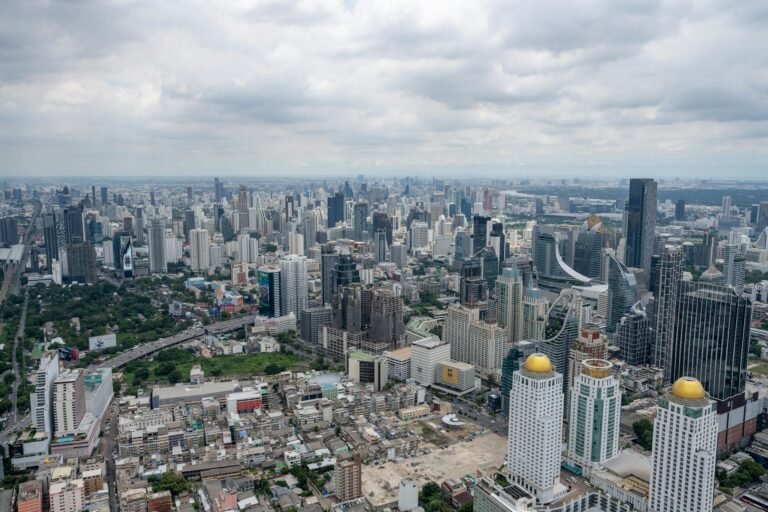 Stunning aerial view of Bangkok's modern skyline under clouded skies.