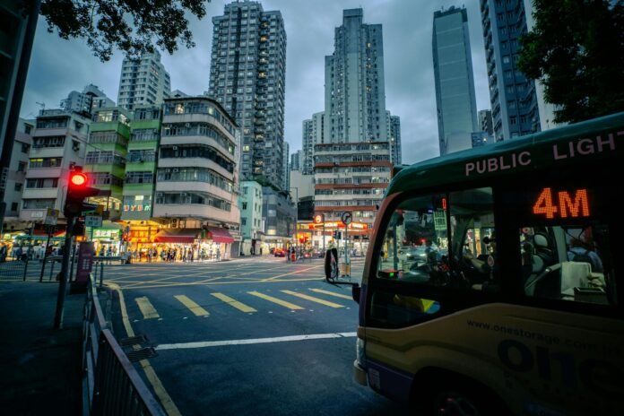 Vibrant city street in Hong Kong at twilight with bustling traffic and towering skyscrapers.