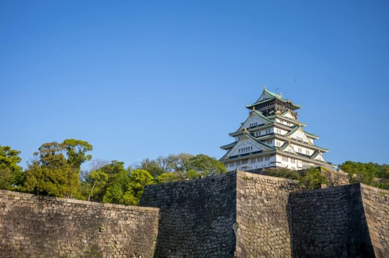 Stunning view of Osaka Castle with its lush greenery, under a clear blue sky.