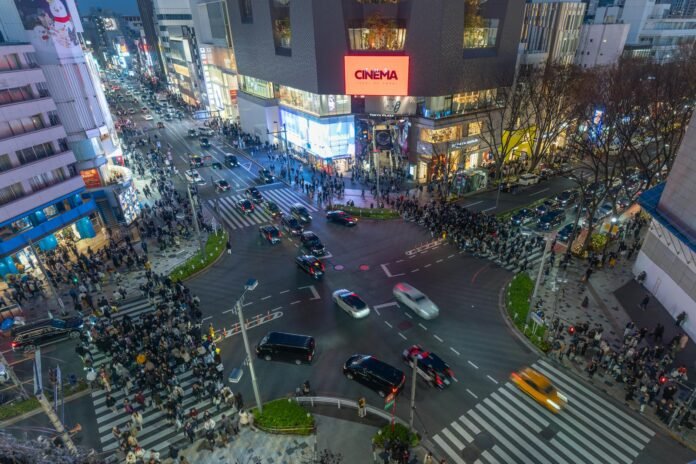 A bustling night view of Shibuya Crossing in Tokyo with crowds and city lights.