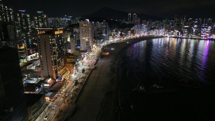 Stunning night view of Busan's skyline and beach, showcasing vibrant city lights.