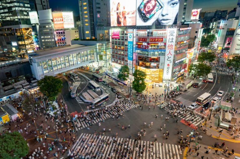 Shibuya Scramble Crossing in Tokyo teems with life, illuminated by vibrant city lights at night.