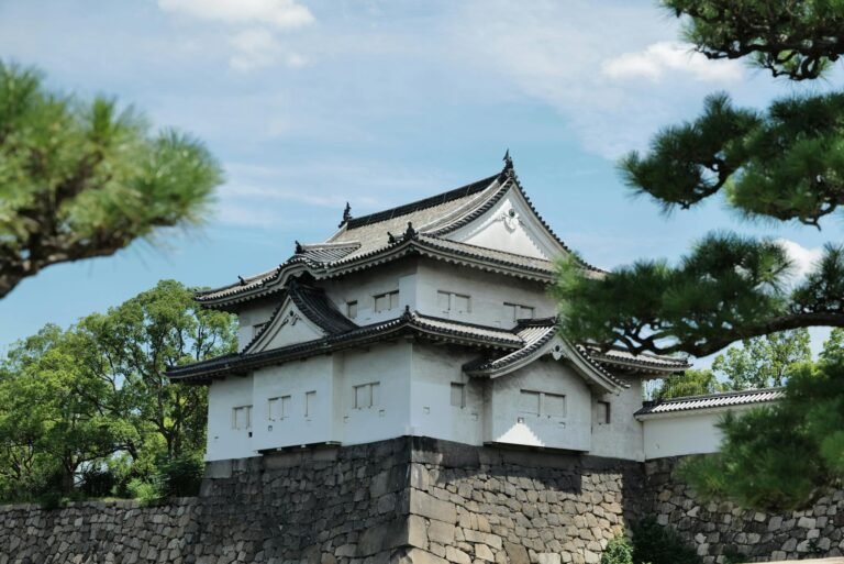 A beautiful view of a traditional Japanese castle surrounded by lush greenery in Osaka, Japan.