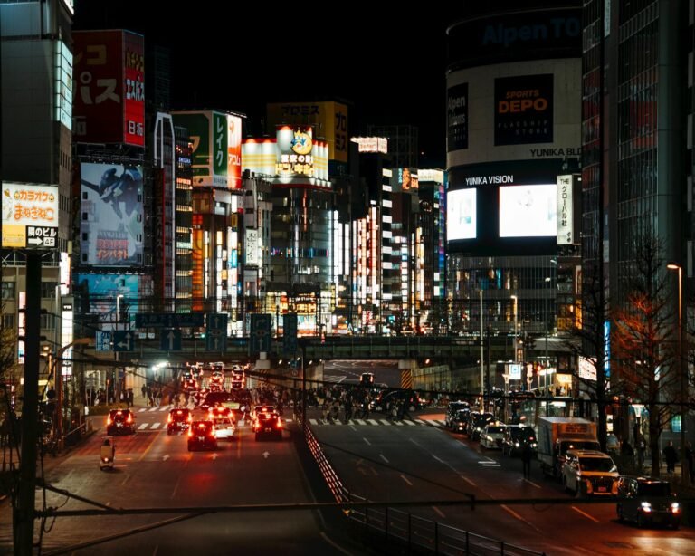 Bright urban scene in Shinjuku, Tokyo, filled with neon lights and bustling traffic at night.
