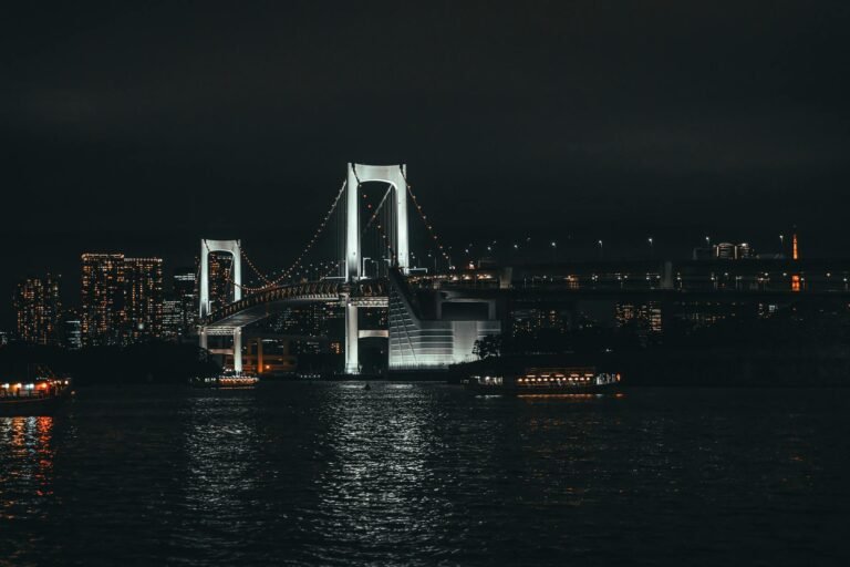Stunning night view of the illuminated Rainbow Bridge in Tokyo, Japan with city skyline.
