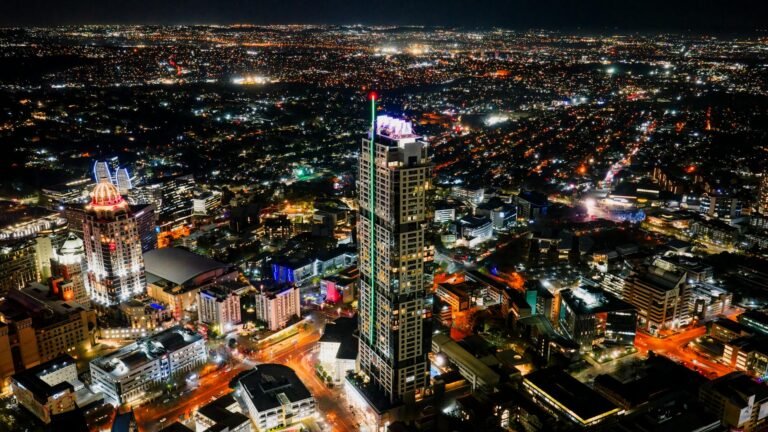 A stunning aerial photograph of Sandton's illuminated skyline at night, showcasing vibrant city lights and skyscrapers.