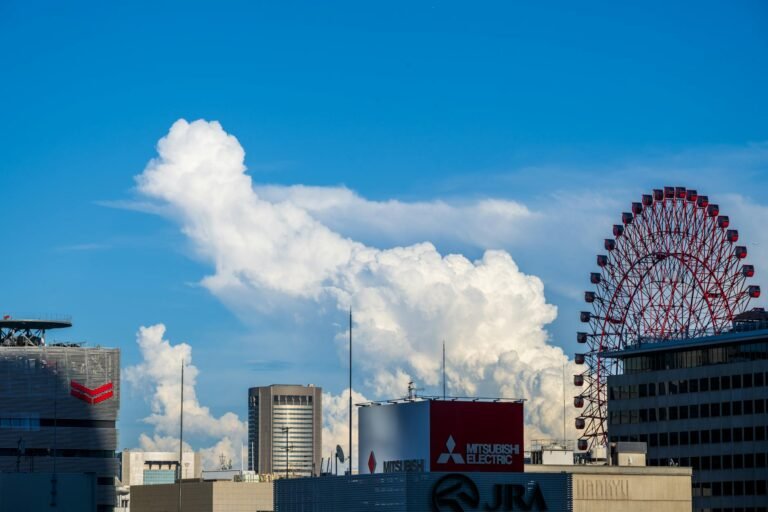 Vibrant urban skyline featuring towering buildings and a ferris wheel under a striking cloud formation.