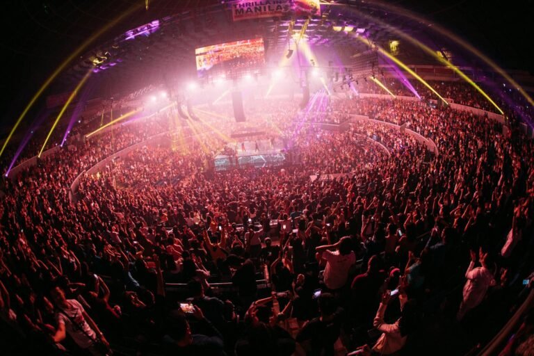 Vibrant crowd enjoying a live concert in a bustling Manila arena at night.