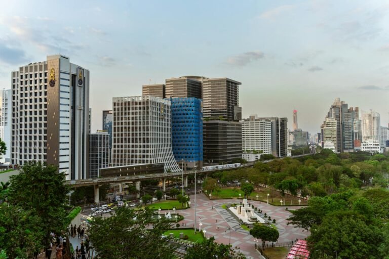 Aerial view of modern skyscrapers and greenery in Bangkok city during daytime, showcasing urban architecture.