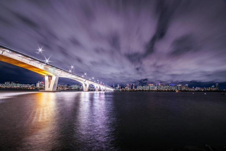 Stunning long-exposure night shot capturing the Seoul skyline reflecting on the river with dazzling bridge lights.
