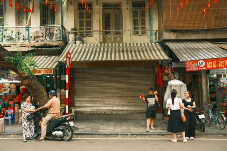 A lively street scene in Hanoi, Vietnam featuring people interacting on a bustling sidewalk.