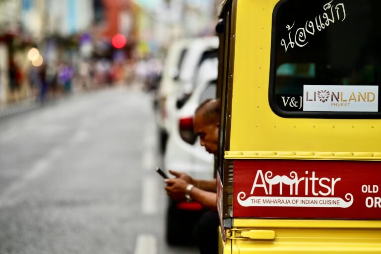 A vibrant street scene in Phuket featuring a tuk-tuk adorned with Indian restaurant signage.