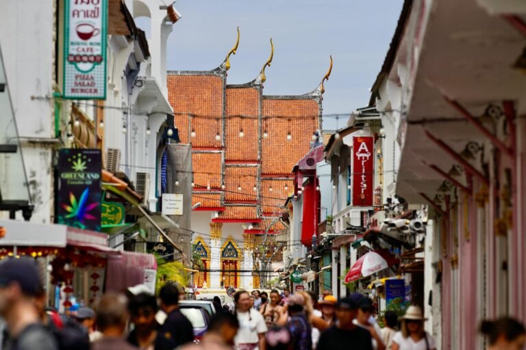 Vibrant street scene in Phuket, Thailand, showcasing traditional architecture and a busy crowd.
