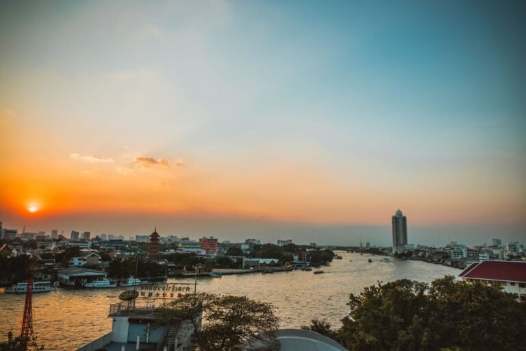 Stunning sunset view over Bangkok's Chao Phraya River with cityscape and skyline.