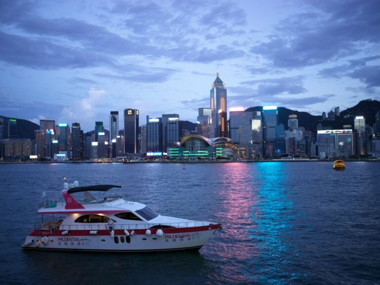 Stunning evening view of Hong Kong Harbor highlighting a yacht and skyline reflections.