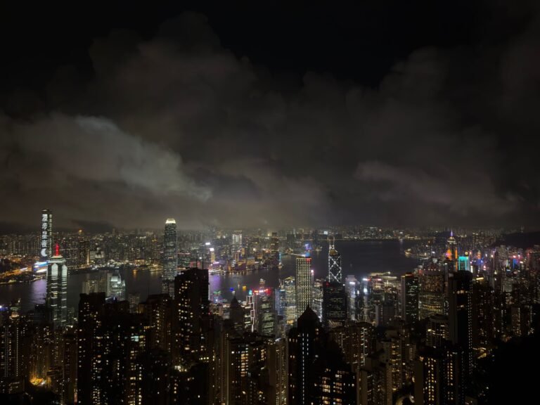 Stunning nighttime cityscape of Hong Kong with illuminated skyscrapers and dramatic clouds.
