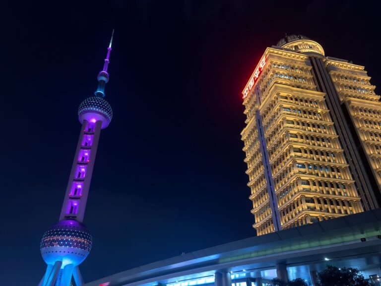Stunning night view featuring the Oriental Pearl Tower and a lit-up skyscraper in Shanghai, China.